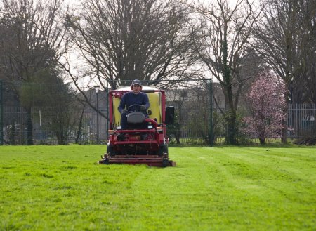 Tondeuse à gazon rouge sur un terrain de sport vert